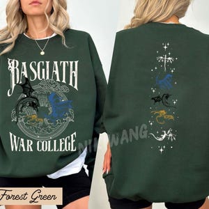 Puede incluir: Sudadera verde bosque con texto "Basgiath War College" y gr&aacute;ficos de dragones en la parte delantera. La parte trasera presenta siluetas de dragones. La sudadera es de estilo c&oacute;modo e informal.