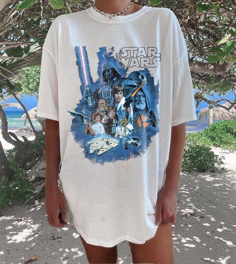 May include: White t-shirt with a blue and white graphic print of characters from the Star Wars movie franchise. The text "Star Wars" is printed in black on the shirt.