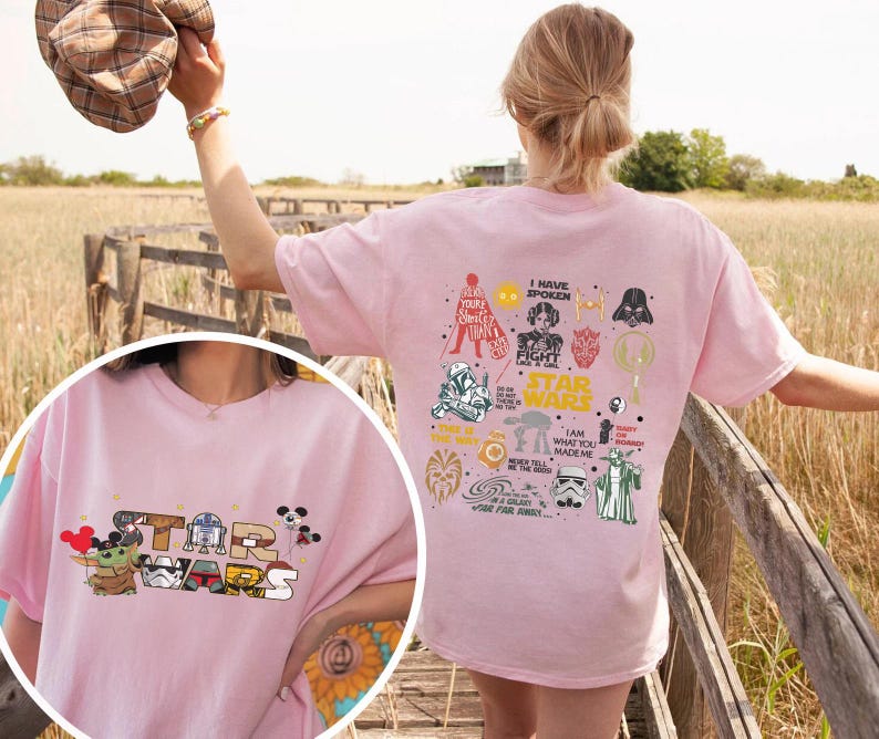 May include: A light pink Star Wars t-shirt with the Star Wars logo and characters like Grogu and R2-D2. The back displays Star Wars graphics and text. The tee shirt is made of a soft material.