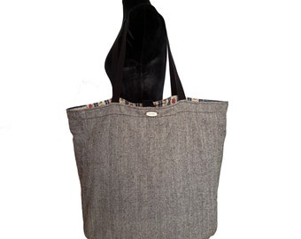 May include: A large gray and black tote bag with a black strap. The bag has a patterned lining with red, white, and blue accents.