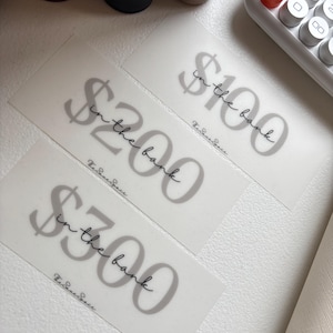May include: A set of three ceramic mugs with a speckled, matte finish. The mugs are in shades of cream, light gray, and dark gray. Each mug has a simple, minimalist design, perfect for coffee or tea.