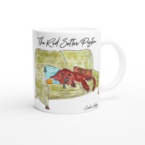 May include: White ceramic mug with a watercolour illustration of a red setter dog relaxing on a green armchair. The dog is lying on a blue cushion with a yellow ball. Text reads "The Red Setter Position."