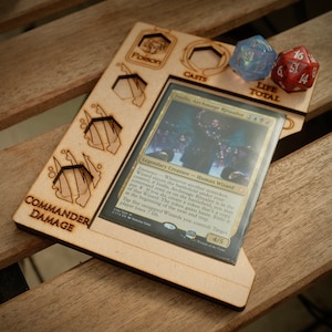 May include: A wooden game board with a card slot, dice holders, and a life total tracker. The card slot holds a Magic: The Gathering card featuring Inalla, Archmage Ritualist. The board has a "Commander Damage" label and a "Poison" icon.