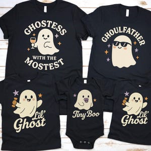 Może przedstawiać: Czarne koszulki na Halloween dla rodziny i body dla niemowląt. Koszulki mają grafiki duchów z napisami takimi jak "Ghostess with the Mostest", "Ghoulfather" i "Lil' Ghost". Body ma napis "Tiny Boo".