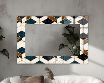 May include: A rectangular wall mirror featuring a decorative border with a geometric pattern of hexagons in navy blue, white, and copper tones. The mirror surface reflects a plant with large dark green leaves, creating a clear visual contrast.