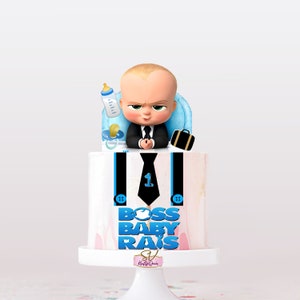 Peut inclure: Un gâteau blanc avec un marbrage rose et blanc. Le gâteau est décoré d'une figurine en fondant de Boss Bébé, d'une cravate bleue, de bretelles noires et des mots "Boss Bébé Rais" en lettres bleues. Le gâteau est sur un support à gâteau blanc.