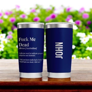 Può includere: Due bicchieri in acciaio inossidabile blu navy. Un bicchiere ha il testo "Fuck Me Dead" con una definizione. L'altro bicchiere ha il nome "JOHN" in testo bianco.