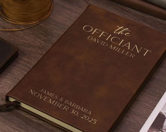 Könnte beinhalten: Ein braunes Notizbuch in Lederoptik mit goldener Prägung, die oben "the OFFICIANT DAVID MILLER" und unten "JAMES & BARBARA NOVEMBER 30, 2025" zeigt. Das rechteckige Notizbuch hat eine glatte, matte Oberfläche und ein integriertes Lesezeichen.