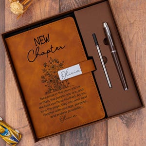 May include: A brown leather journal set in a gift box. The journal is embossed with "NEW Chapter" and floral designs, with the name "Olivia" on a metal plate. Includes a pen and refill.