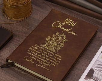 Könnte beinhalten: Ein braunes Notizbuch mit goldener Schrift, die New Chapter liest, einer Blumenillustration und einem Zitat über den Stolz auf die geschriebene Geschichte, das mit dem Namen Sophia Johnson endet. Der Einband ist glatt und hat ein Lesezeichen.
