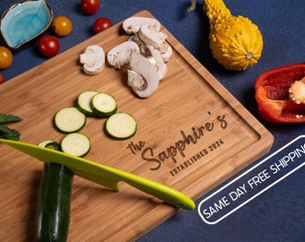 Könnte beinhalten: Ein rechteckiges Bambus-Schneidebrett mit Saftrille, graviert mit dem Text "The Sapphire's ESTABLISHED 2024". Das Brett ist umgeben von geschnittenen Pilzen, Zucchinischeiben, Kirschtomaten, einem gelben Zierkürbis und einer roten Paprika.