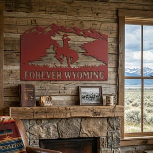 May include: A red metal wall sign featuring a silhouette of a cowboy riding a bucking horse against a mountain backdrop, with the text FOREVER WYOMING cut out at the bottom. The sign is mounted on a horizontal wooden wall above a stone fireplace.