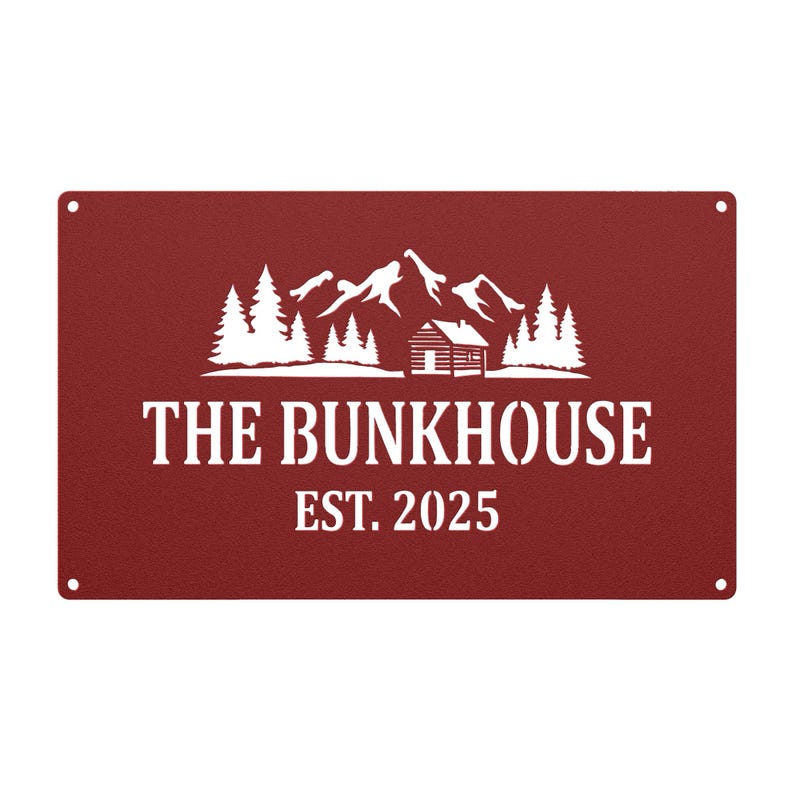 May include: A rectangular, burgundy metal sign with white text and a mountain and cabin design. The text reads "THE BUNKHOUSE EST. 2025". The sign has four holes, one in each corner.