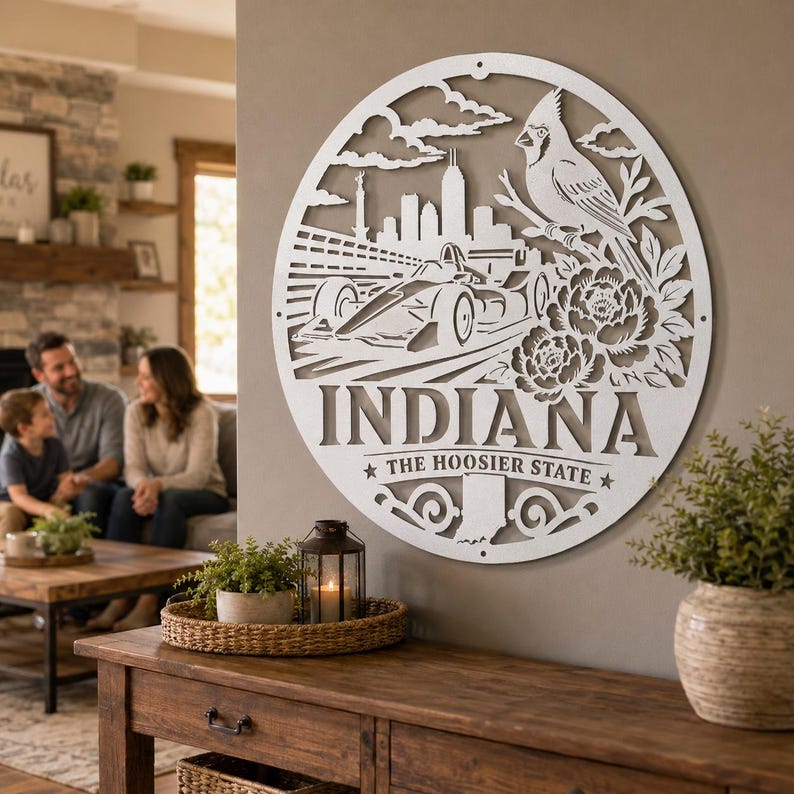 Może przedstawiać: Biała metalowa dekoracja ścienna w kształcie koła. Projekt przedstawia samoch&oacute;d wyścigowy, ptaka, kwiaty i napis "INDIANA". Tekst "THE HOOSIER STATE" jest r&oacute;wnież zawarty.