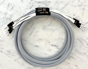 May include: Gray speaker wire with a white mesh outer covering. The wire is coiled and has a label that reads "mule" three times.