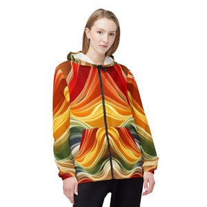 May include: A hooded zip-up jacket with a colorful abstract pattern in shades of red, orange, yellow, green, and blue. The pattern resembles flowing waves or ribbons.