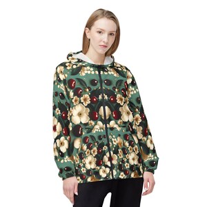 May include: A green hooded jacket with a floral print featuring white flowers and red cherries. The jacket has a zip closure and long sleeves.