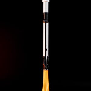 May include: A vertical image of a toy rocket ship against a black background. The rocket has a white nose cone, a white and black body, and an orange flame effect at the base, sitting on a white base.