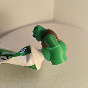 Shrek Toothpaste Dispenser Tip – Funny Cartoon Character Who Poops Toothpaste Gadget for Kids & Adults Bathroom Accessory
