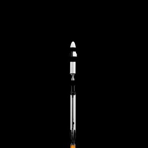 May include: A white and black model rocket with an orange and white base, set against a black background. The rocket is segmented, with a conical top and a detailed engine section. The base emits a stylized orange flame.