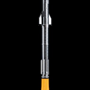 May include: A silver rocket model with a pointed nose and detailed body, emitting a bright orange flame from its base. The rocket is set against a black background, with a white cloud-like base.