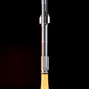 May include: A silver rocket model with a pointed nose and detailed body, emitting a bright yellow flame from its base. The rocket sits on a white cloud-like structure against a black background, creating a dramatic contrast.