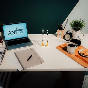 May include: A well-lit desk setup featuring a laptop with the text "ANdruck" on the screen, a notebook, pens, and a coffee break with cookies. Two rocket-shaped objects stand upright. A wire basket holds papers.
