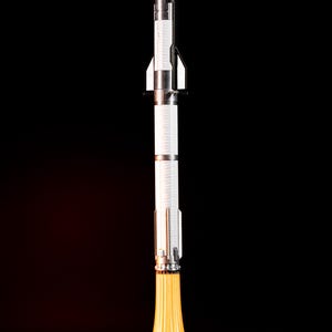 May include: A detailed model rocket with a silver and white body, set against a black background. The rocket has a pointed nose and fins, with a bright yellow flame effect emanating from the base, creating a dynamic visual.