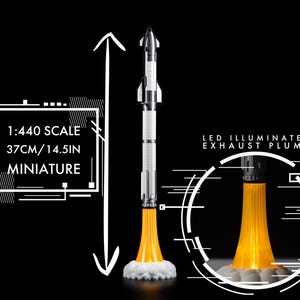 May include: A miniature rocket model, 14.5 inches tall, with a white and silver body and an illuminated orange exhaust plume. The model is labeled as 1:440 scale and includes the text "LED Illuminated Exhaust Plume".