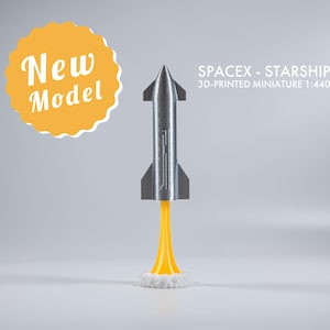 May include: A 3D-printed miniature SpaceX Starship model, scale 1:440, with a silver body and yellow flame. The model is labeled "New Model" in a yellow circle.