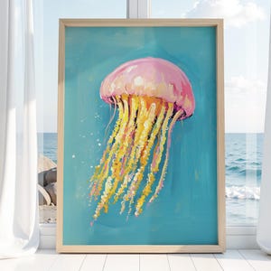 K&ouml;nnte beinhalten: Gerahmtes Gem&auml;lde einer Qualle. Die Qualle ist rosa und gelb mit langen, flie&szlig;enden Tentakeln. Der Hintergrund ist ein leuchtendes T&uuml;rkis. Das Gem&auml;lde wird in einem Raum mit Fenster zum Meer gezeigt.