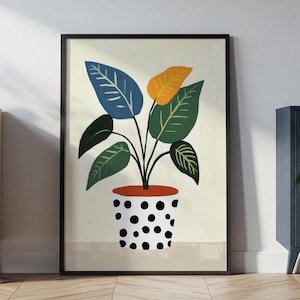 Op de afbeelding: Ingelijste kunstdruk met een gestileerde plant in een pot met stippen. De plant heeft groene, blauwe en gele bladeren. De pot is oranje met zwarte stippen. Het kunstwerk wordt op een lichtbeige achtergrond weergegeven.