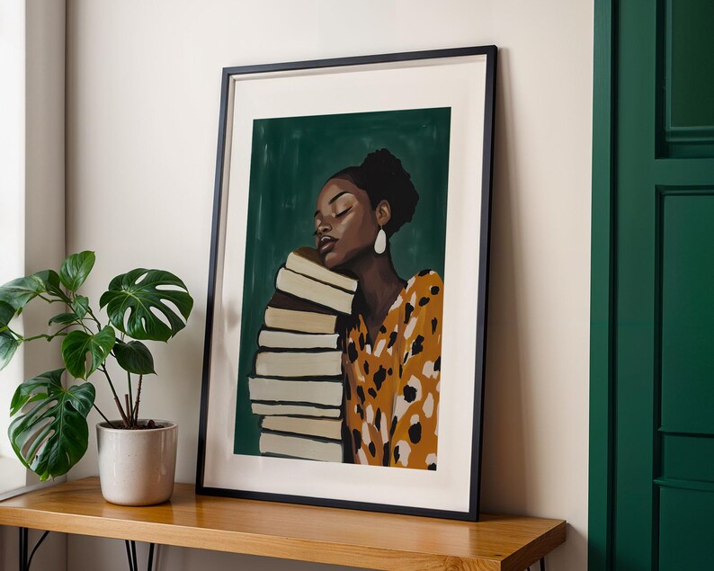 May include: Framed art print featuring a woman with dark skin resting her head on a stack of books. She wears a yellow and brown patterned dress and large white earrings. The background is a dark green color.