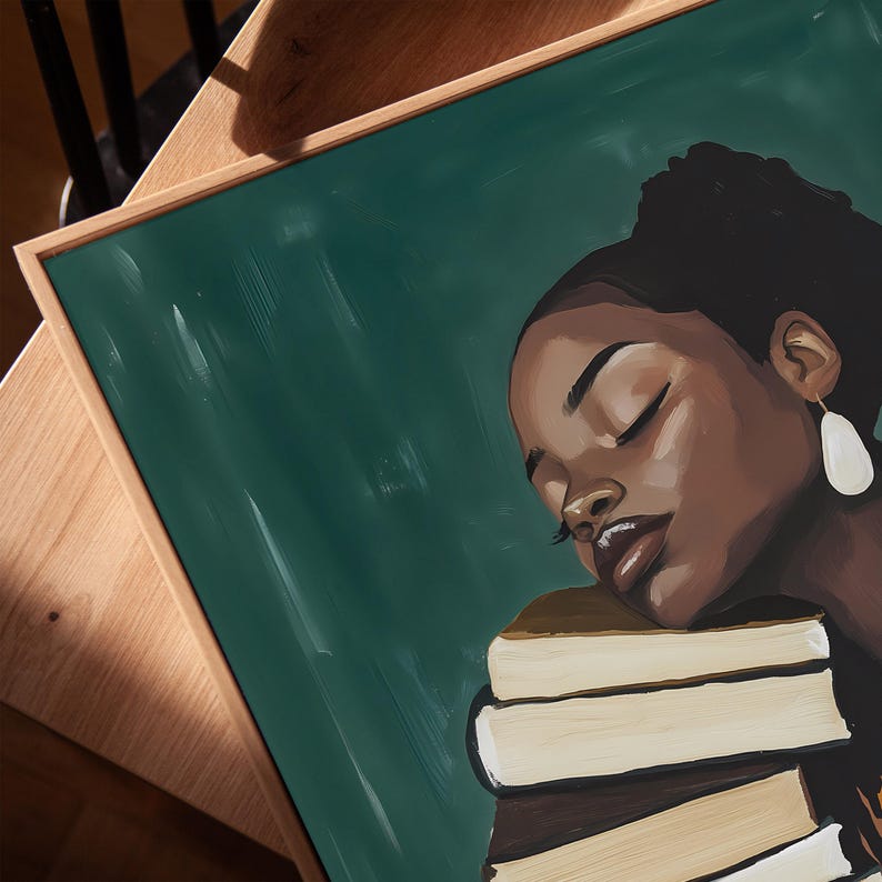 May include: An art print featuring a portrait of a person with dark skin, eyes closed, resting on a stack of books. The background is a dark green color, and the print is framed in a light brown wooden frame.