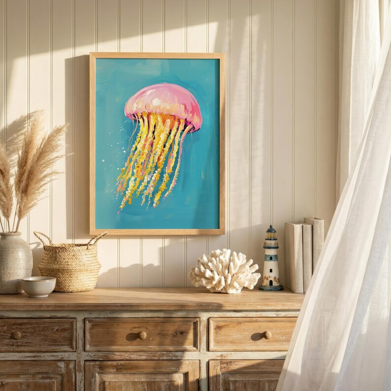 K&ouml;nnte beinhalten: Gerahmter Kunstdruck mit einem Gem&auml;lde einer Qualle. Die rosa und gelbe Qualle sticht vor einem t&uuml;rkisfarbenen Hintergrund hervor. Das Bild ist in einem hellen Holzrahmen, passend f&uuml;r eine Einrichtung im K&uuml;stenstil.
