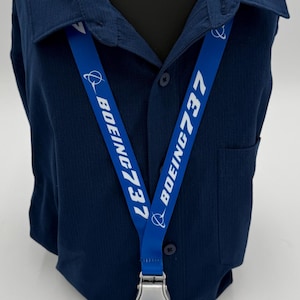 May include: Blue lanyard with white text that reads "BOEING 737" on both sides. The lanyard has a silver clip and a black phone charm.