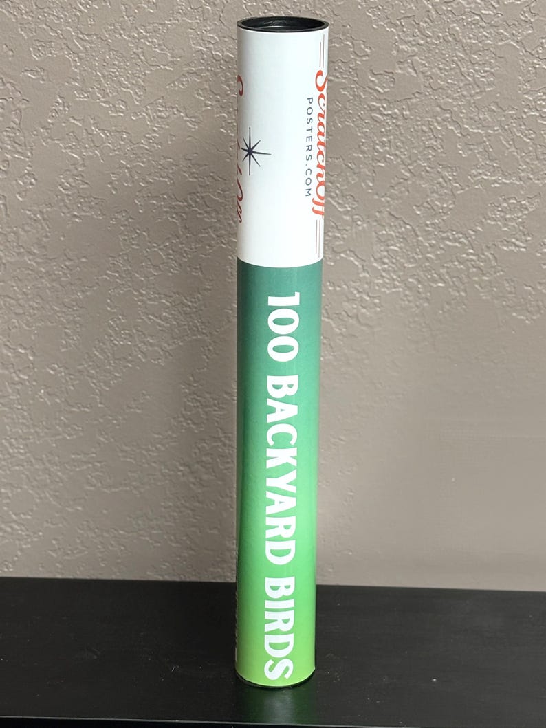May include: A cylindrical cardboard shipping tube with a white top section featuring the red text Scratchoff Posters.com and a black star icon. The lower section is green with the white text 100 BACKYARD BIRDS printed vertically along the side.