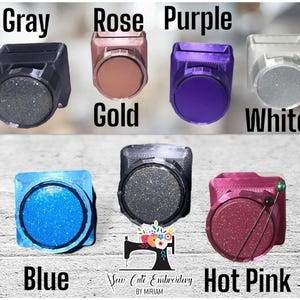 May include: A collection of seven square-shaped magnetic needle minders in various colors including gray, rose gold, purple, white, blue, black, and hot pink. Each minder features a circular center and the text Sew Cute Embroidery BY MIRIAM.