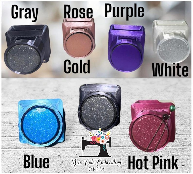 May include: A collection of seven square-shaped magnetic needle minders in various colors including gray, rose gold, purple, white, blue, black, and hot pink. Each minder features a circular center and the text Sew Cute Embroidery BY MIRIAM.