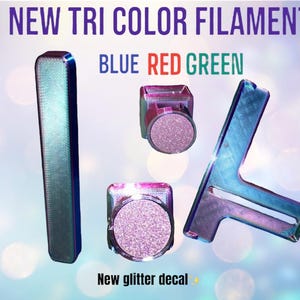 May include: A 3D printed model of the number "1/4" in blue, red, and green filament. The model is made with a glitter decal. "New Tri Colour Filament" and "Blue Red Green" are written above the model.