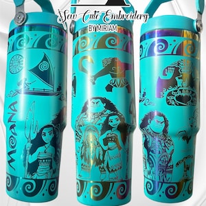 May include: Three turquoise stainless steel tumblers with a Moana theme. The tumblers feature a black and gold design with images of Moana, Maui, and the demigod Te Fiti. The tumblers have a black handle and a black lid.