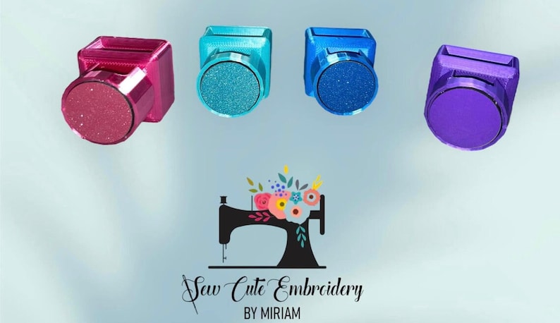 May include: Four square-shaped plastic needle minders in magenta, teal, blue, and purple, each featuring a circular magnetic front. Below them is a black silhouette logo of a sewing machine with a floral arrangement and the text Sew Cute Embroidery BY MIRIAM.