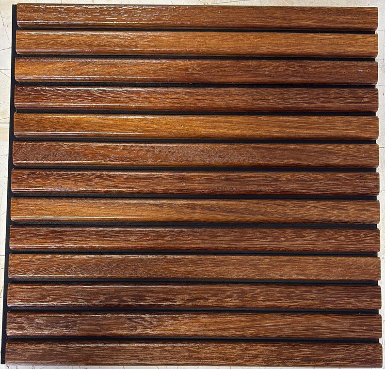 Op de afbeelding: Een vierkant houten paneel met horizontale, gelijkmatig verdeelde, donkerbruine houten latten. De lamellen hebben een glanzende afwerking en worden gescheiden door dunne zwarte lijnen. De houtnerf is zichtbaar en voegt textuur toe.