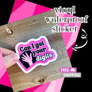 May include: Pink vinyl sticker with the text "Can I get your digits" and a black and white illustration of a hand skeleton.