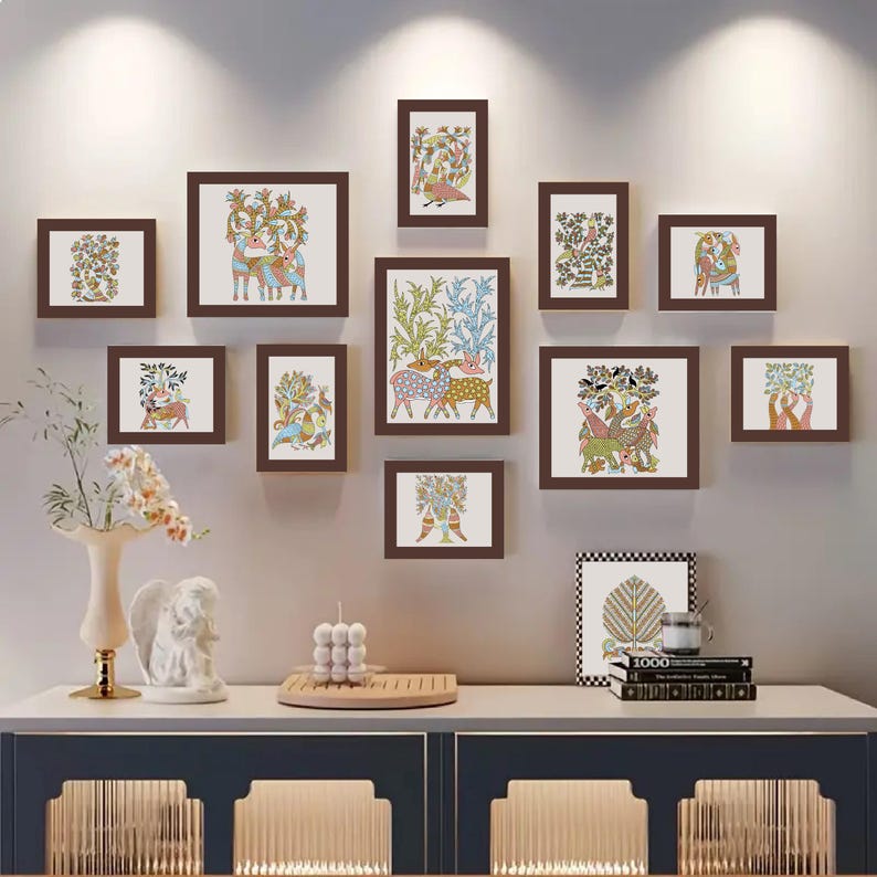 May include: A gallery wall of framed art prints with brown frames, showcasing vibrant illustrations of animals and plants. The artwork is mounted on a light grey wall above a white cabinet with a blue base. Decorative items are on the cabinet.