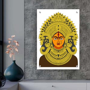May include: A framed artwork depicting a deity with an orange face, embellished with gold and yellow details. The artwork is mounted on a white background and displayed against a grey textured wall.