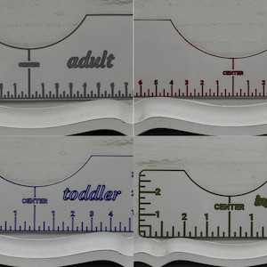 May include: A set of four white plastic foot measuring tools. Each tool is labeled for different age groups: adult, youth, toddler, and infant. Each tool has a curved top and a ruler with inch markings. The text "CENTER" is printed on each tool.