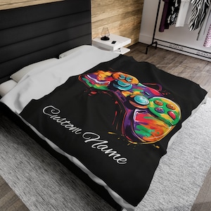 May include: A black and white throw blanket with a colorful video game controller graphic and the text "Custom Name".