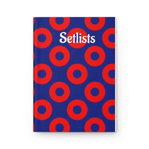 May include: A hardcover notebook with a blue background and a pattern of red circles. The word "Setlists" is printed in white across the top. The notebook is a practical item for musicians and songwriters.