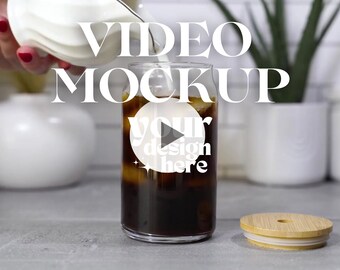 May include: A glass of iced coffee with a white lid and a play button icon that says "your design here" on the side. The text "VIDEO MOCKUP" is written in white letters on a black background.
